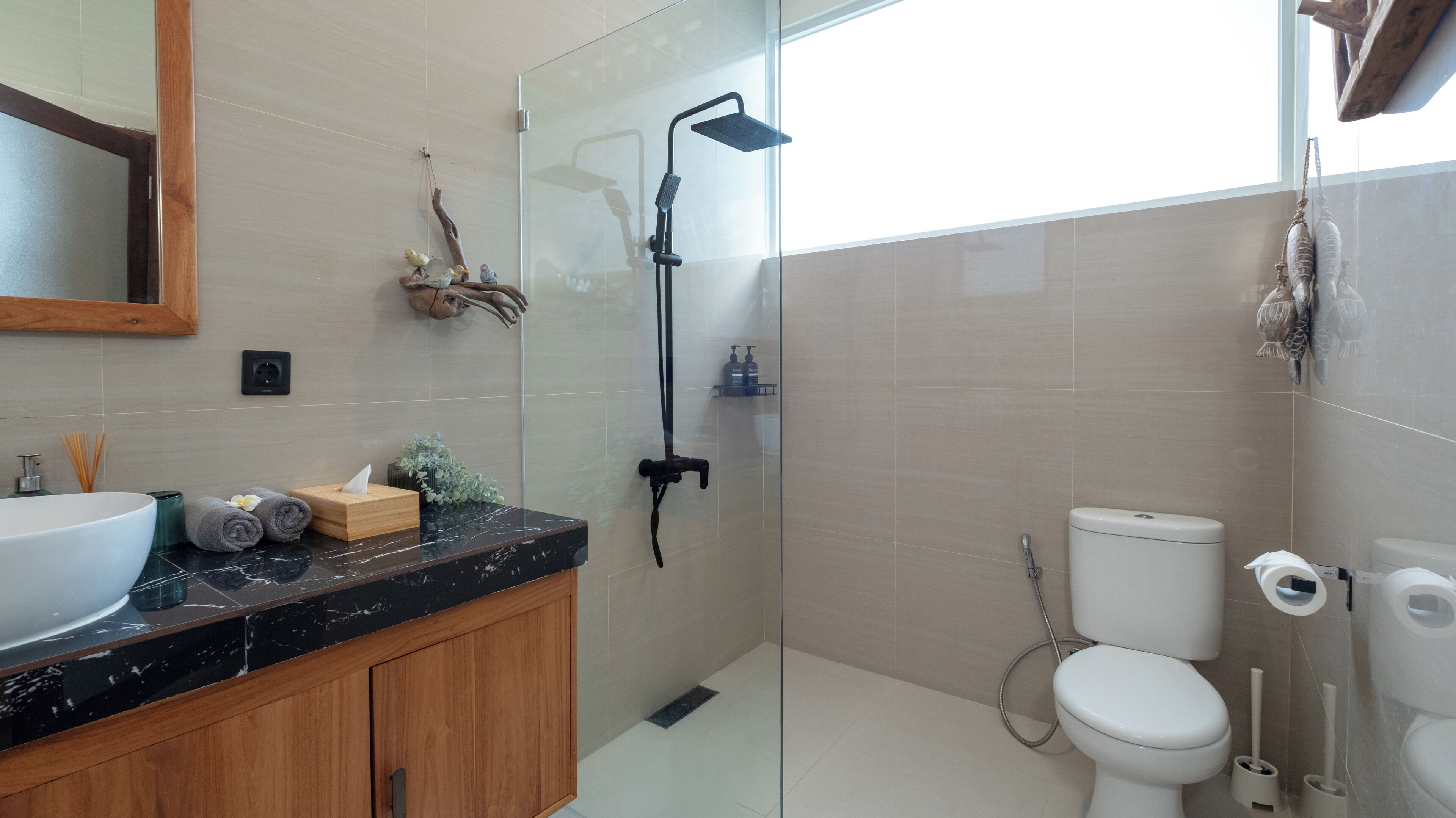 Een moderne badkamer met een douchecabine van glas, een wit toilet en een marmeren wastafel.