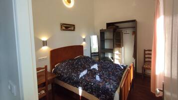 Une chambre avec un lit en bois, une table de chevet, une armoire et une étagère intégrée.
