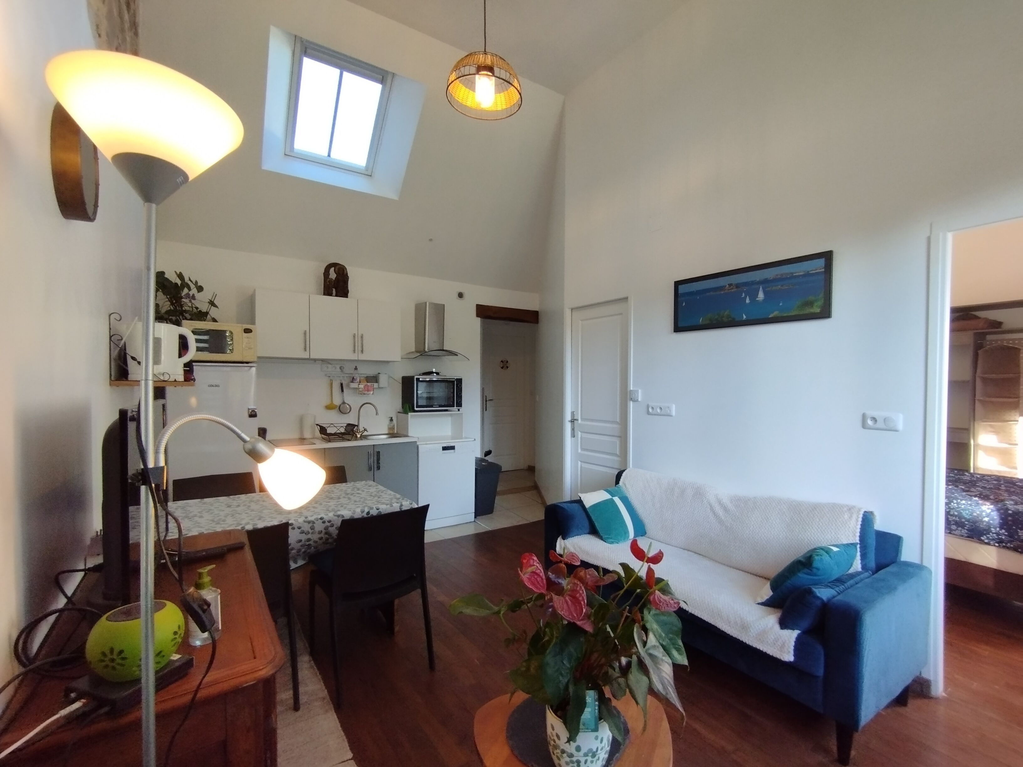 A compact living space with a kitchenette, a dining area, and a seating area with a couch and a table.