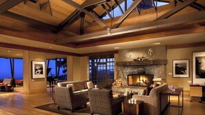 Un salón espacioso con chimenea de piedra, ventanas amplias y un piano de cola.