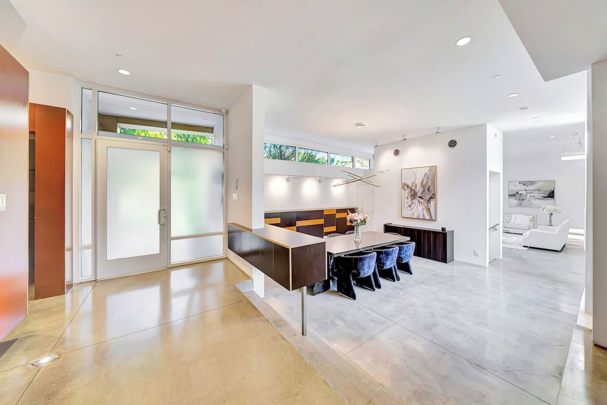 Una cocina moderna con una isla central, una zona de comedor con sillas y vistas al exterior.