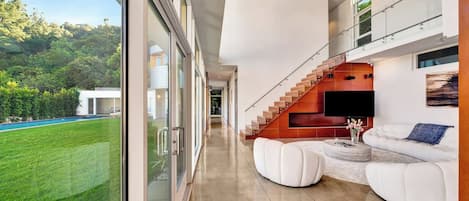 Un interior moderno con una escalera, un televisor de pantalla plana y un sofá blanco.