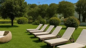 A row of sun loungers on a grassy lawn with trees in the background. - Marina studios (Corfu)