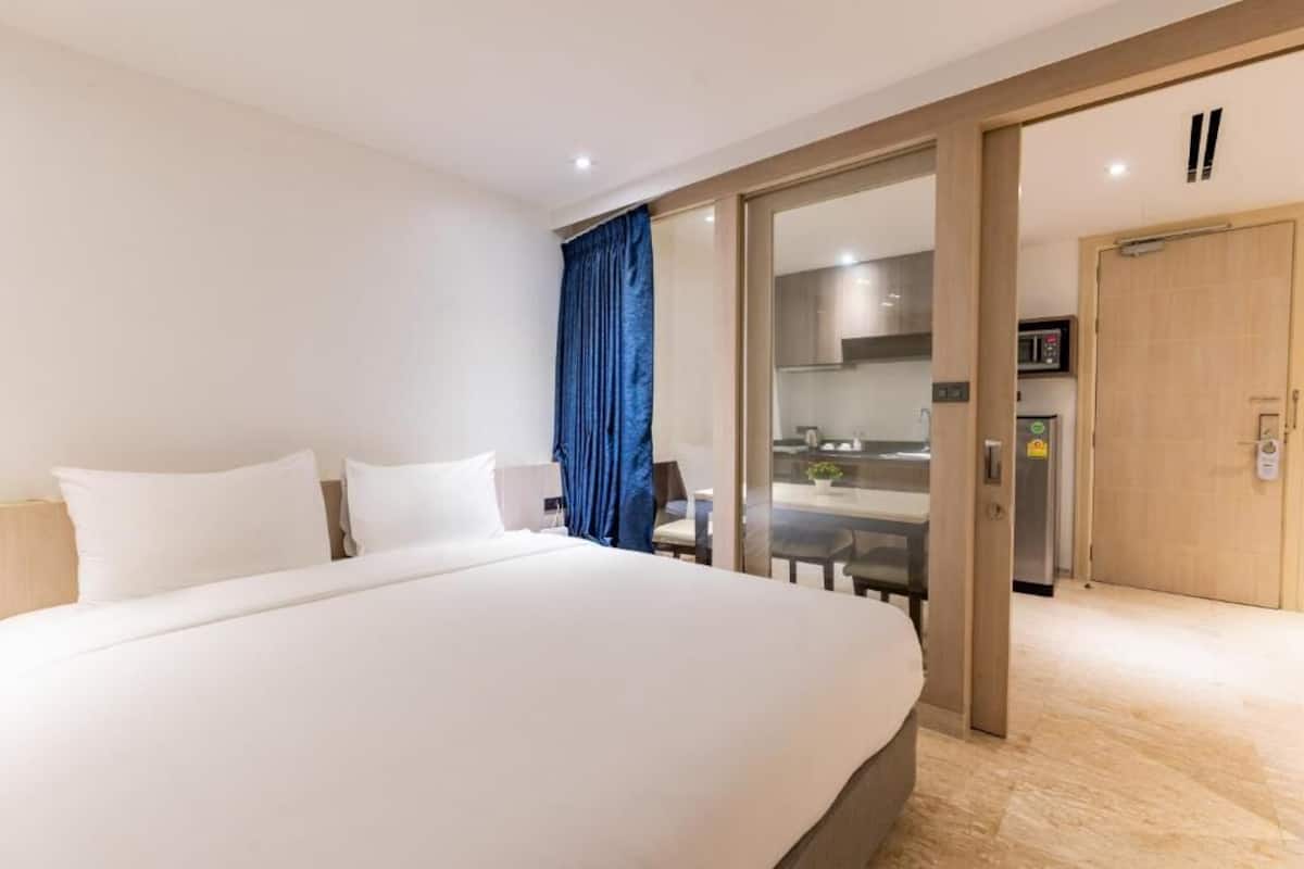 Une chambre d’hôtel avec un grand lit, une porte coulissante donnant sur un coin cuisine et une vue sur la salle à manger.