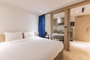 A hotel room with a large bed, a sliding door to a kitchenette, and a view of the dining area. - Sukhothai Residence Ruamrudee (Bangkok)