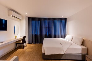 A hotel room with a bed, a desk with a chair, a TV, and an air conditioning unit. - Sukhothai Residence Ruamrudee (Bangkok)