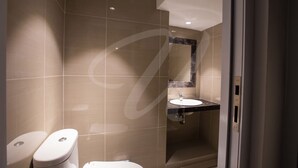 Et moderne badeværelse med toilet, bidet og håndvask under et spejl.