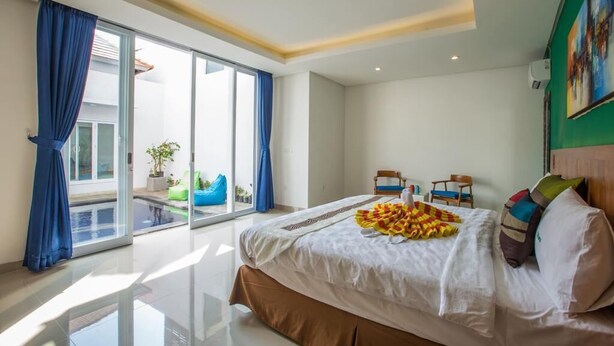 Et moderne hotelværelse med en stor seng, en balkon med blå gardiner og udsigt til en swimmingpool.
