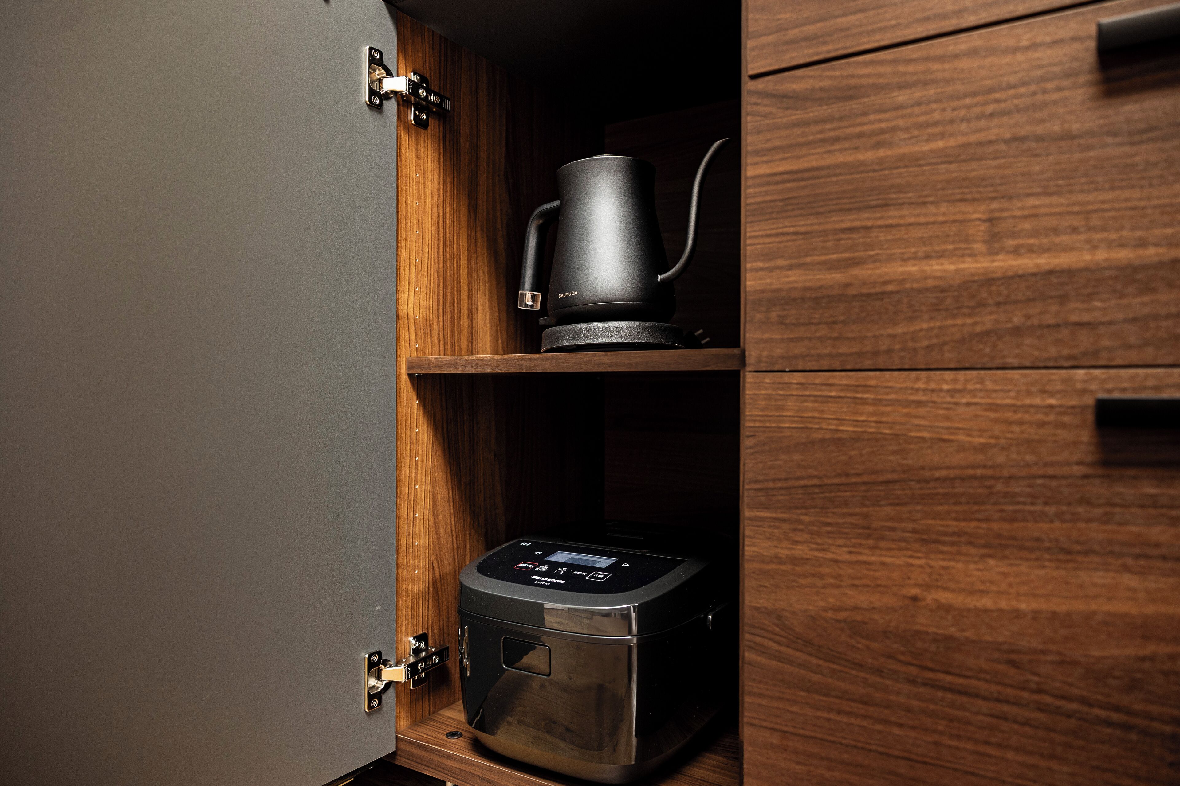 A kitchen with a coffee maker and a rice cooker on wooden shelves.