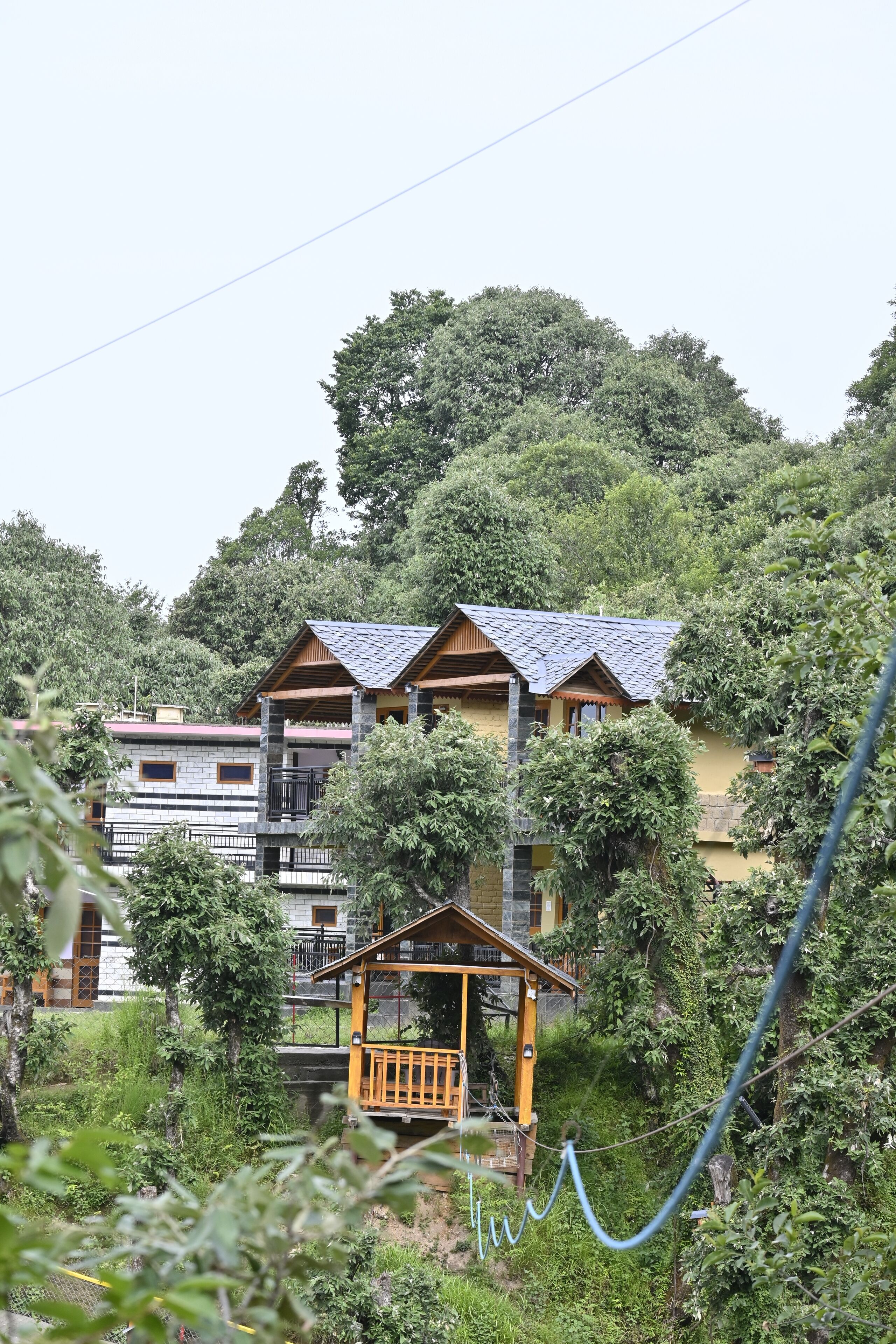A hillside property with multiple buildings, including a main house and a smaller structure with a balcony.