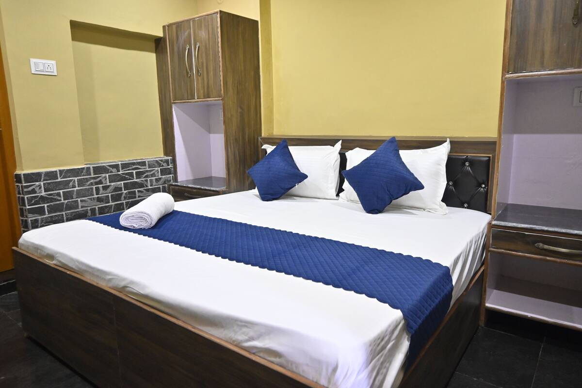 A neatly made bed with a blue quilt, white linens, and two blue pillows.