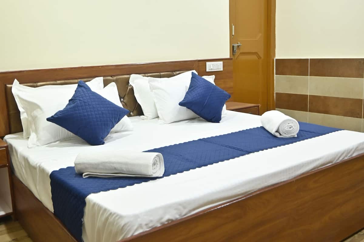 A neatly made bed with white and blue bedding, a wooden headboard, and a wooden floor.