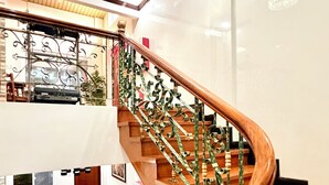 Una imponente escalera con barandales de metal ornamentados y acabado de madera, que conduce a un piso superior.