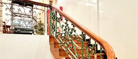 A grand staircase with ornate metal railings and a wooden finish, leading to an upper floor.