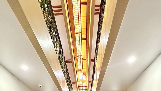 Un pasillo de hotel con un camino central, flanqueado por mesas y sillas, que conduce a un árbol de Navidad decorado.