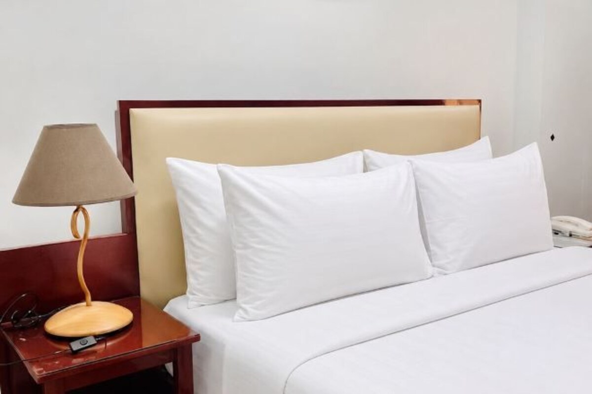 Una habitación de hotel con una cama, una mesita de noche con lámpara y un teléfono.