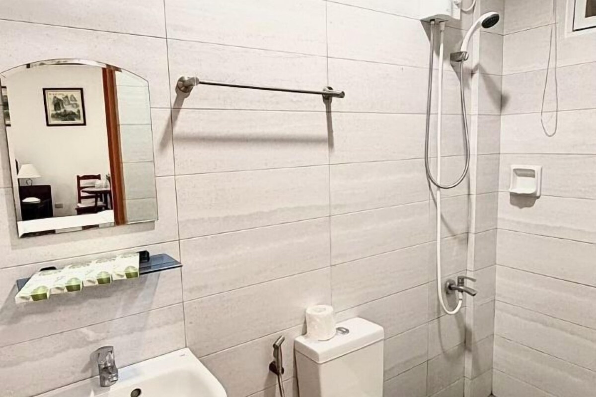 Ein Badezimmer mit Waschbecken, Spiegel, Handtuchhalter, Dusche und Toilette.
