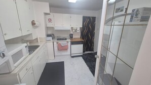 Eine kompakte Küche mit weißen Schränken, einer Mikrowelle, einem Toaster und einem kleinen Kühlschrank.