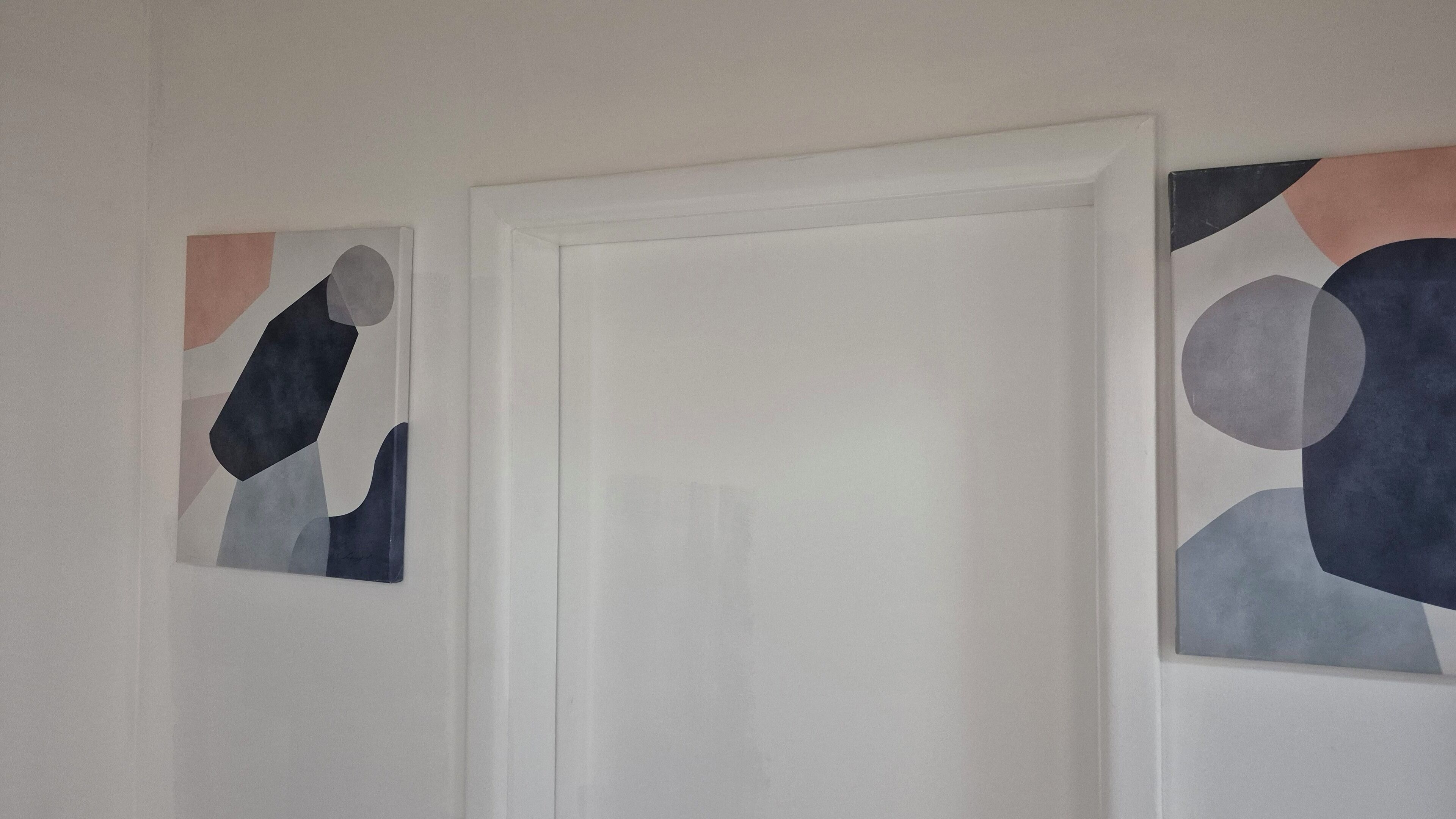 Ein Zimmer mit einer weißen Tür und abstrakter Kunst an den Wänden.