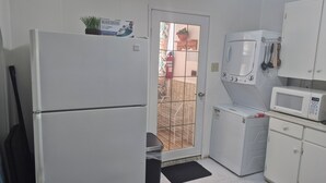 Eine kleine Küche mit Kühlschrank, Mikrowelle und einer Waschmaschine.