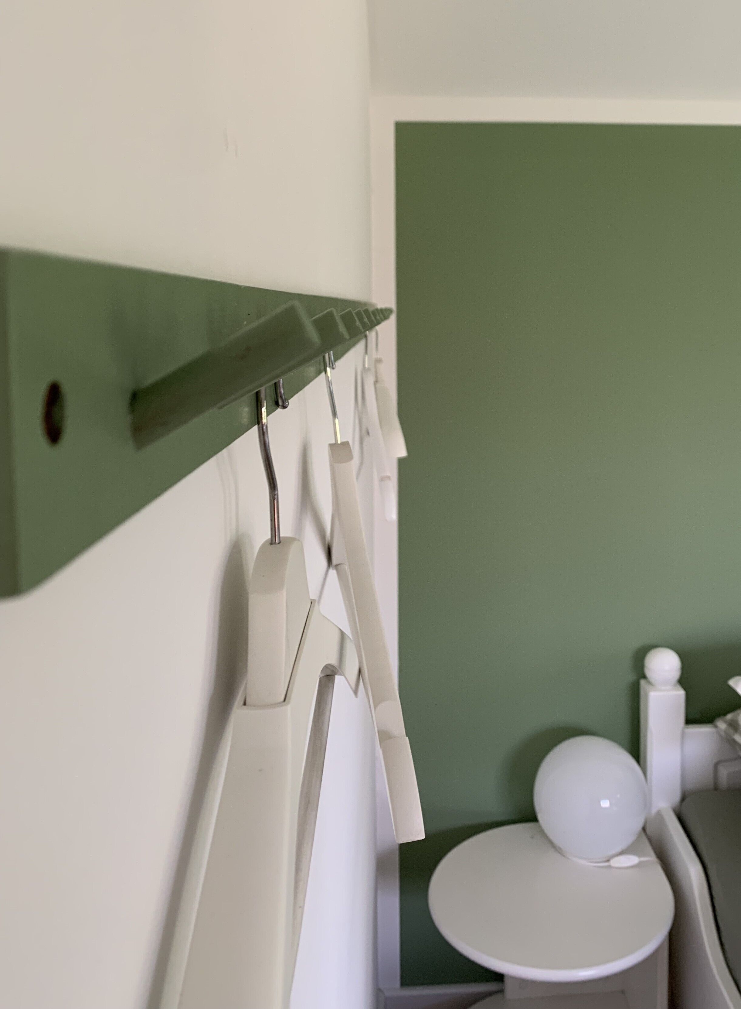 Une salle de bain avec des toilettes, un lavabo blanc et un mur vert.