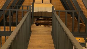 A cozy attic bedroom with a wooden sloped ceiling, a bed, and a small wooden staircase. - EHLI BUNGALOV (Sapanca)