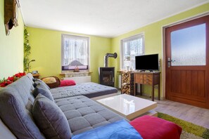 A living room with a sofa, a television, a fireplace, and a door.