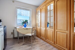 A kitchen with a window, a table with chairs, and wooden cabinets.