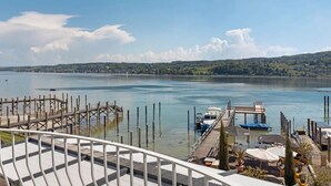 A waterfront view with a dock, a boat, and a distant town. - Room 'Mit Seeblick Und Balkon' with Lake View, Shared Terrace and Wi-Fi (Reichenau)