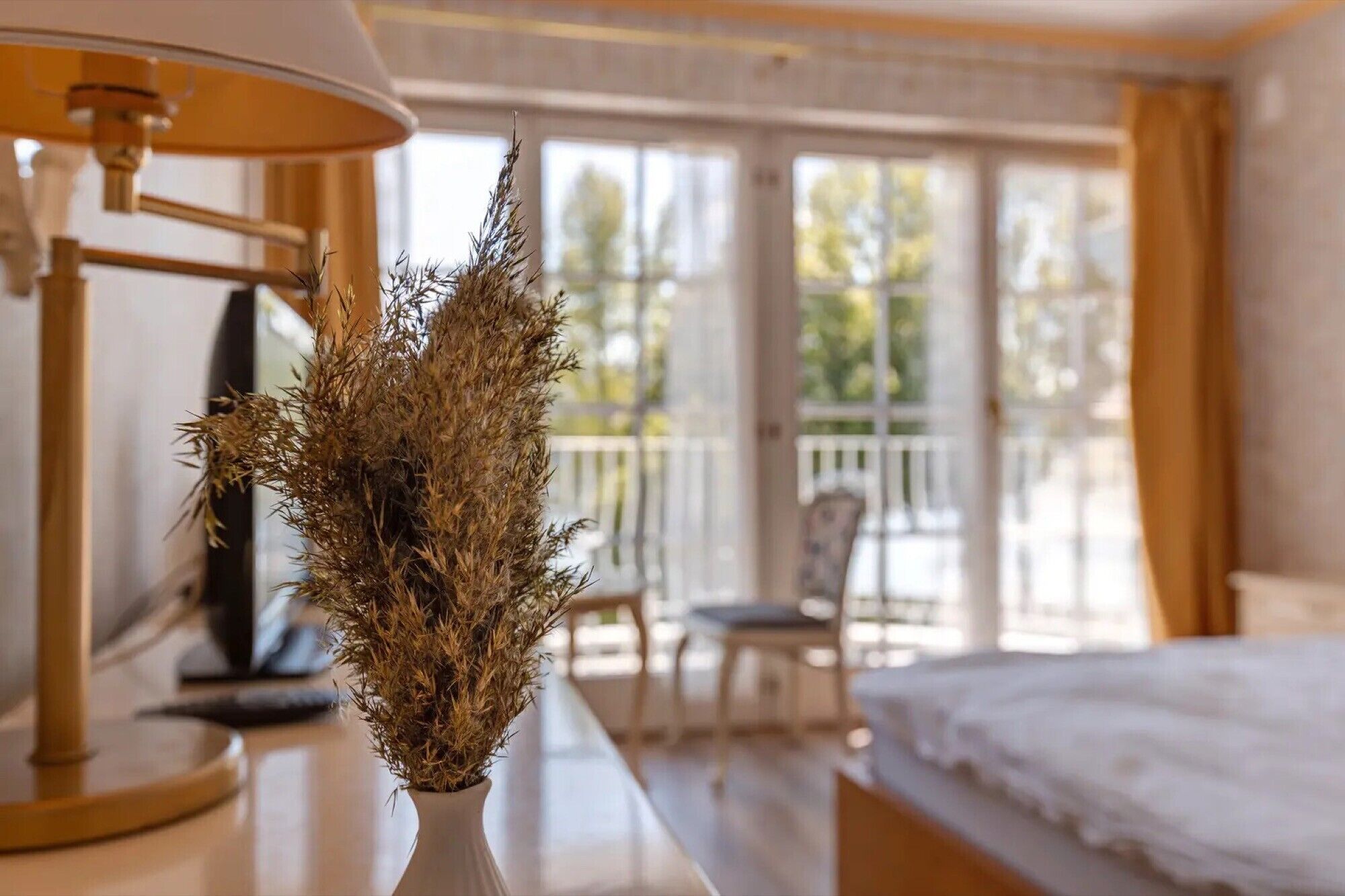 A hotel room with a bed, a chair, a table, and a window with a view of the outdoors.