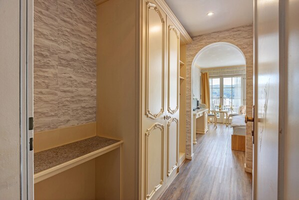 A hallway with a marble wall, a wooden floor, and a view of a dining area with a table and chairs. - Room 'Mit Seeblick Und Balkon' with Lake View, Shared Terrace and Wi-Fi (Reichenau)