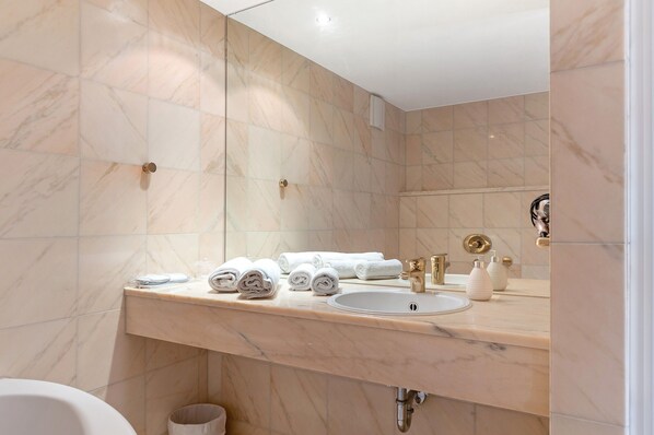 A bathroom with marble walls, a sink, and a mirror.