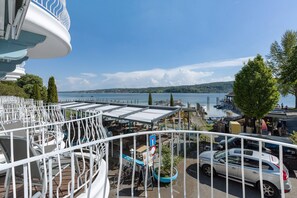 A seaside view with a dining area, a car, and a boat dock.
