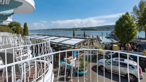 A balcony with a view of a lake, outdoor seating, and a parked car. - Room 'Mit Seeblick Und Balkon' with Lake View, Shared Terrace and Wi-Fi (Reichenau)