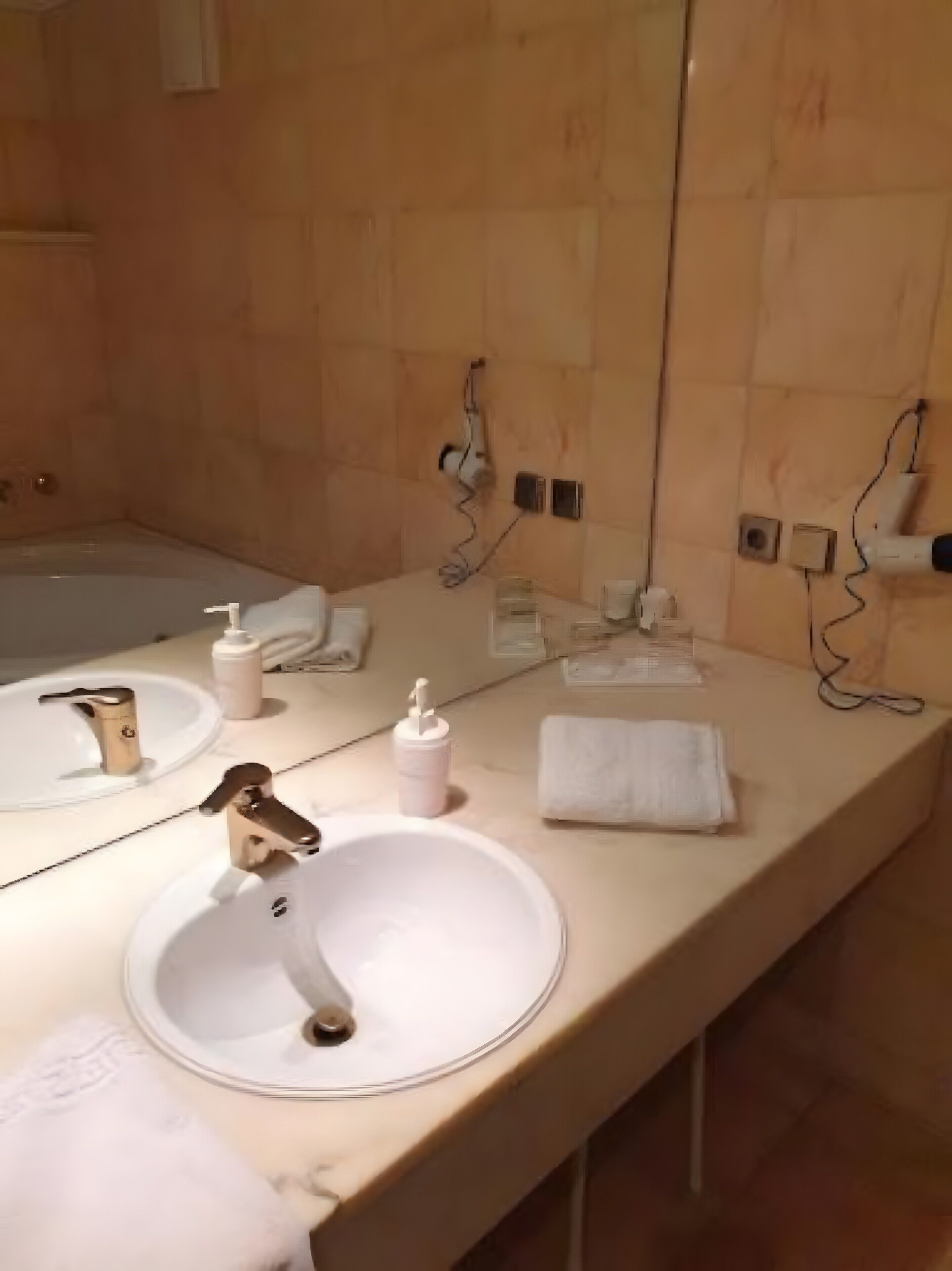 Et badeværelse med et stort spejl, to håndvaske, et badekar og en bøjle til håndklæder.