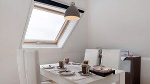 Un comedor con una mesa dispuesta para cuatro personas, una lámpara de techo y vistas del cielo a través de un tragaluz.