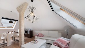 Un loft moderno con comedor, sofá blanco y lámpara de araña.