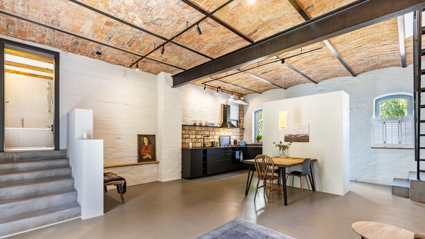 A spacious interior with a kitchen, dining area, and staircase. - Apartment in Former Horse Stable (Angermünde)