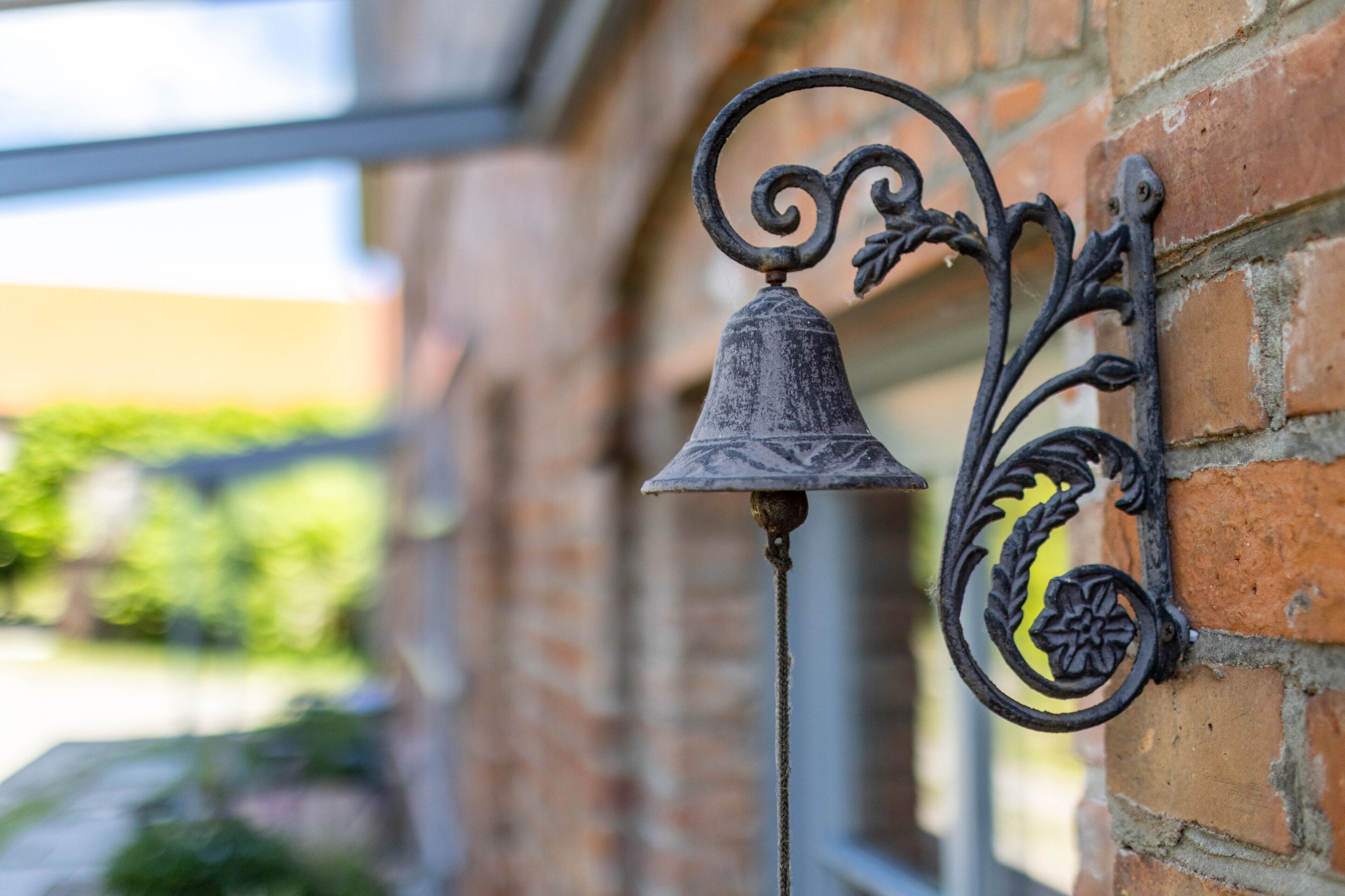 A metal bell attached to a brick wall.