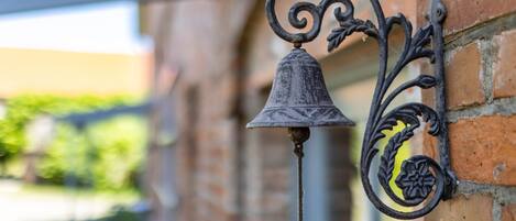 A metal bell attached to a brick wall.