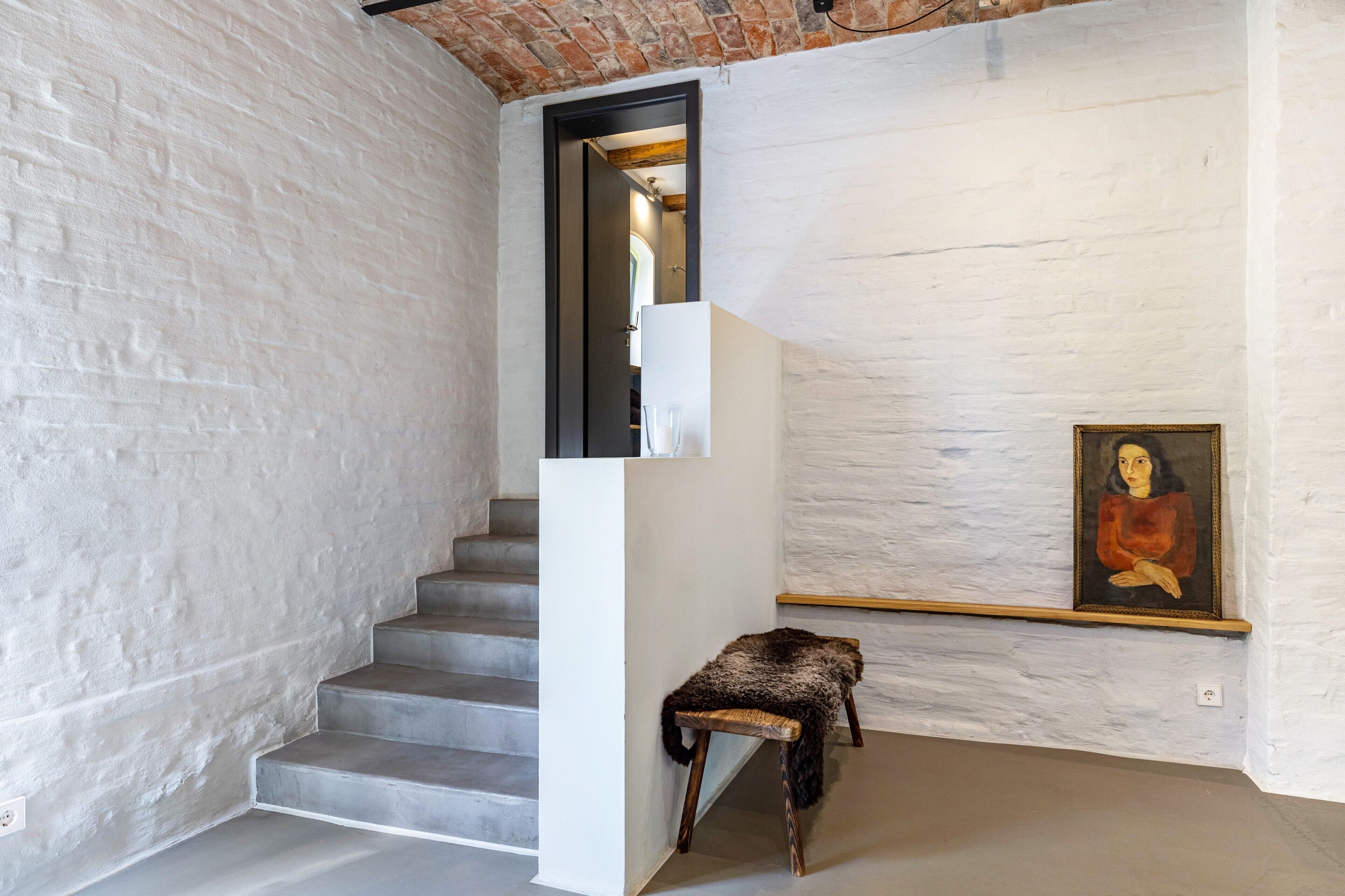 A staircase with white walls and a painting on the wall.