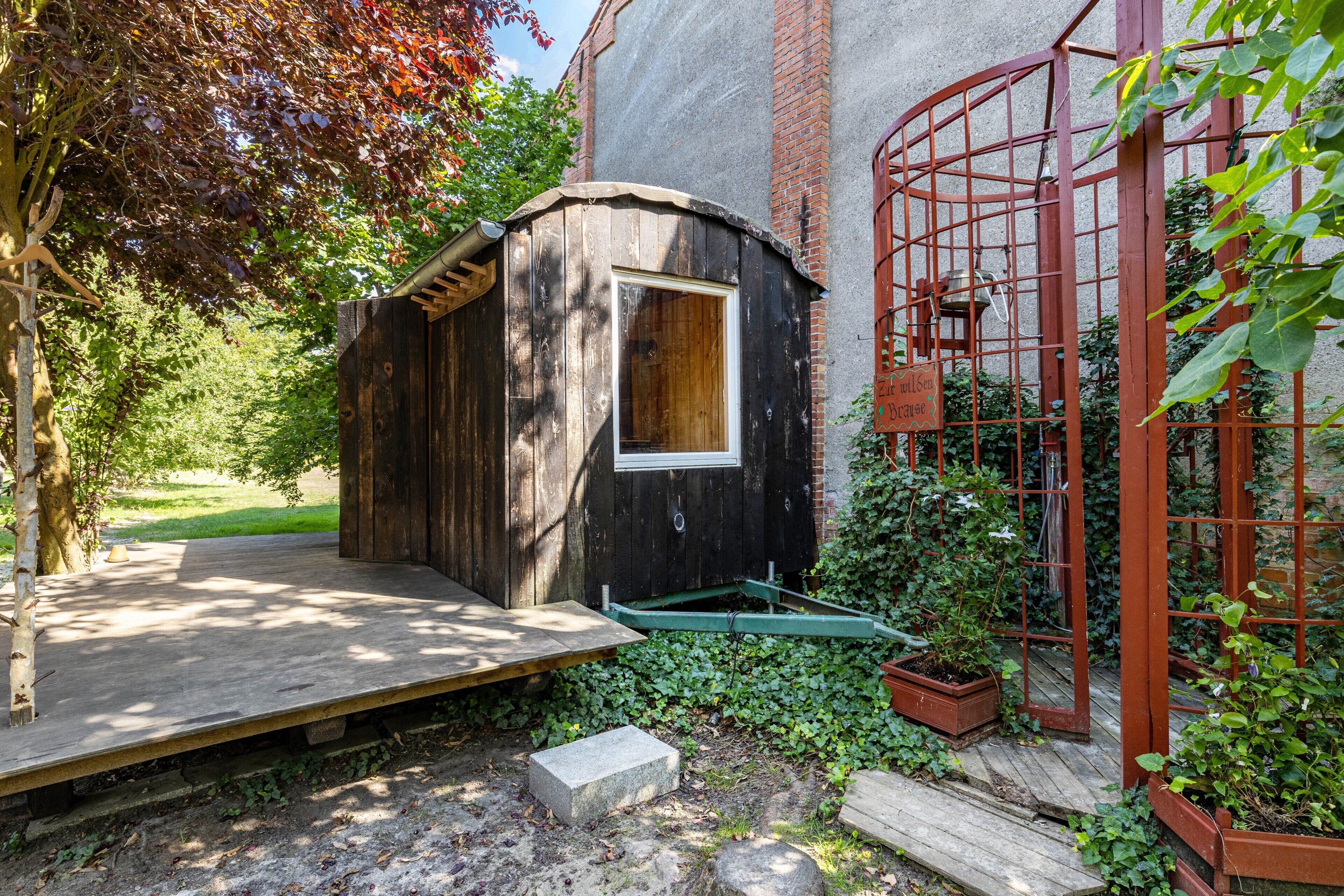 Een houten constructie met een raam, een metalen poort en een houten terras.