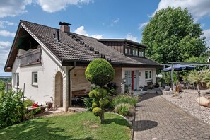 A house with a sloped roof, a small front porch, and a well-maintained garden. - Apartment 'Gerhard Lang' with Private Terrace, Shared Garden and Wi-Fi (Bad Bellingen)