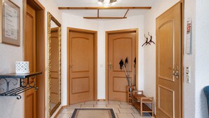 A hallway with wooden doors, a small bench, and a rug.