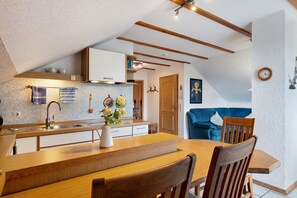 A modern kitchen with a wooden dining table, a sink, and a vase of flowers. - Apartment 'Gerhard Lang' with Private Terrace, Shared Garden and Wi-Fi (Bad Bellingen)