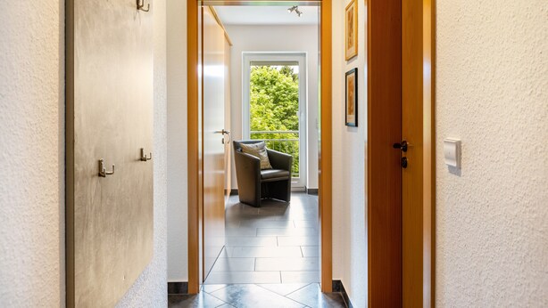 Un pasillo con una puerta que da a una habitación con vistas a zonas verdes.