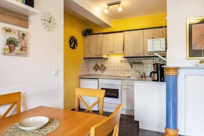 Una cucina con mobili in legno, un forno a microonde e un'area pranzo con tavolo e sedie.