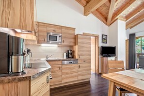 Una cocina moderna con armarios de madera, un microondas integrado y una cafetera.