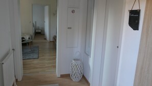 Passadís amb terra de fusta, parets blanques i una porta amb el símbol de no fumar.