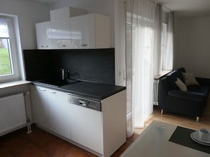 Eine kleine Küche mit weißen Schränken, einer schwarzen Arbeitsplatte und einem eingebauten Geschirrspüler.